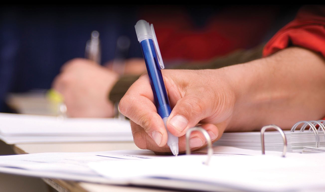 A hand holding a pen, writing notes