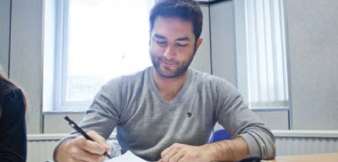One male student writing with a pen in class